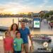 A happy family watching a colorful Mardi Gras parade on a ferry while utilizing a free Disney water taxi service in 2026