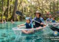 A family enjoying outdoor adventures for families in Orlando at a scenic Florida spring with clear water and kayaks